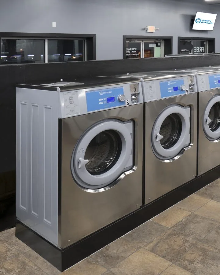 A row of Electrolux coin-operated washers along a laundromat counter