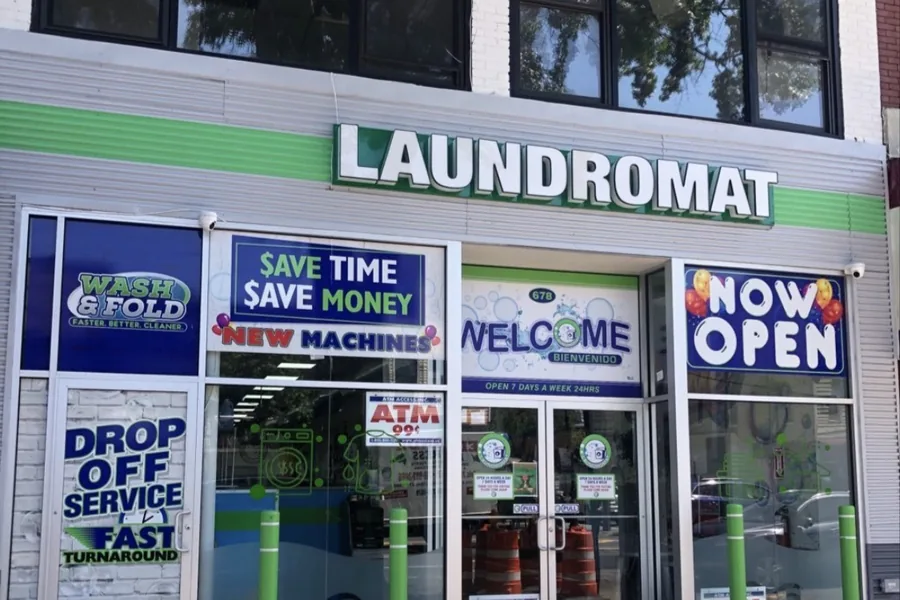 Newly opened laundromat storefront with Now Open and New Machines signs in the windows