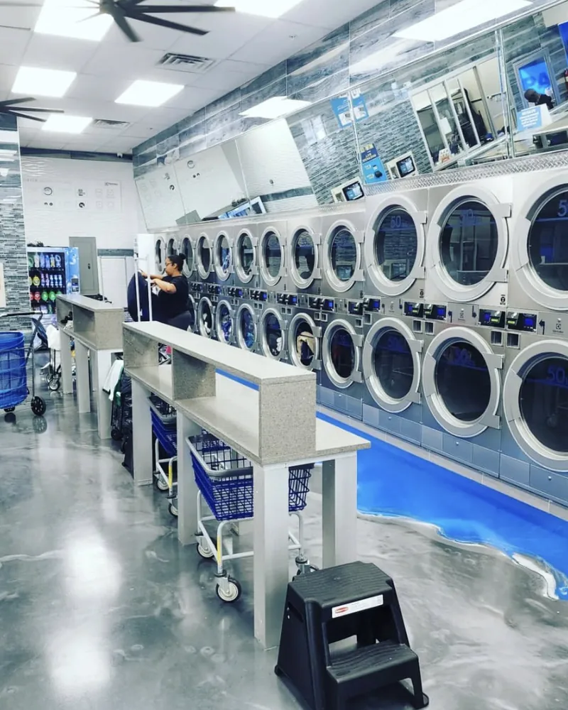 A finished coin laundromat equipped by Masters Laundry, with a full wall of vended dryers and folding tables